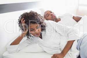 Annoyed woman lying in bed with boyfriend