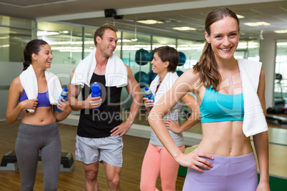 Fit woman smiling at camera in busy fitness studio