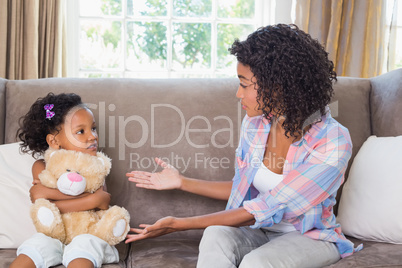 Pretty mother sitting on couch with petulant daughter