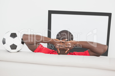 Football fan sitting on couch with ball