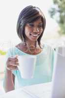 Pretty woman sitting outside using laptop having coffee