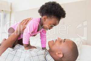 Father and baby girl lying on bed together