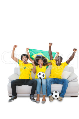 Cheering brazilian football fans in yellow on the sofa