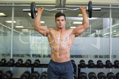 Shirtless muscular man lifting barbell in gym