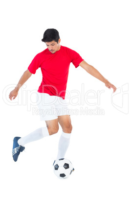 Football player in red kicking ball