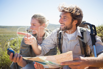 Hiking couple taking a break on mountain terrain using map and c