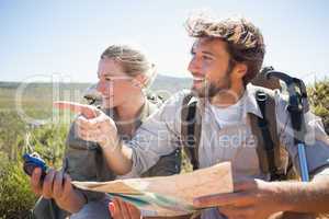 Hiking couple taking a break on mountain terrain using map and c