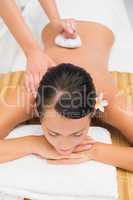 Peaceful brunette enjoying a herbal compress massage