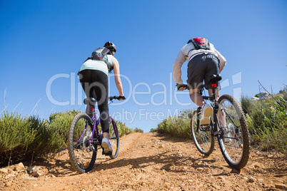 Active couple cycling uphill on a bike ride in the country