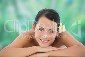Beautiful brunette relaxing on massage table smiling at camera