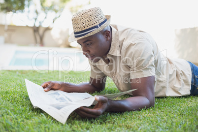 Smiling man relaxing in his garden reading newspaper