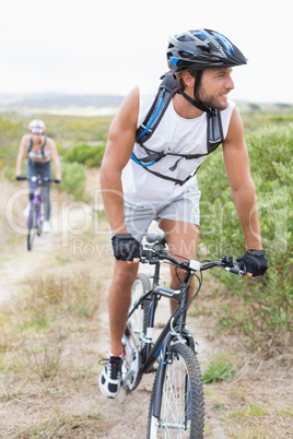 Fit attractive couple cycling on mountain trail