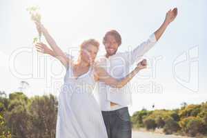 Attractive couple standing with arms raised by the road