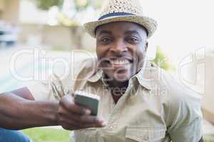 Smiling man relaxing in his garden texting on phone