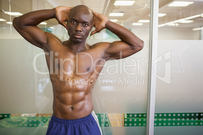 Serious shirtless muscular man posing in gym