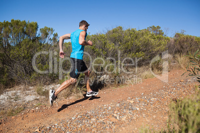 Athletic man jogging up country trail