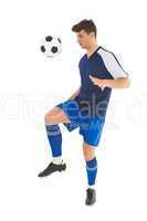 Football player in blue jersey kicking ball