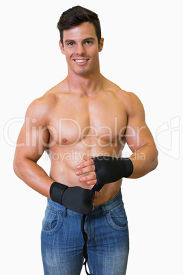 Shirtless muscular man binds bandage on his hand