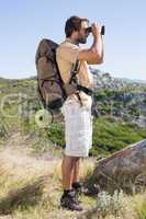 Handsome hiker looking through binoculars