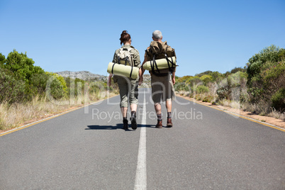 Hitch hiking couple holding hands on the road