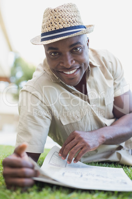 Smiling man relaxing in his garden reading newspaper