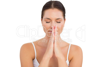 Peaceful brunette meditating with hands together