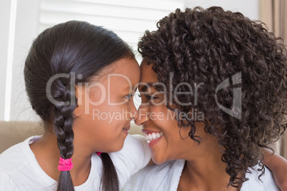 Pretty mother sitting on the couch with her daughter hugging