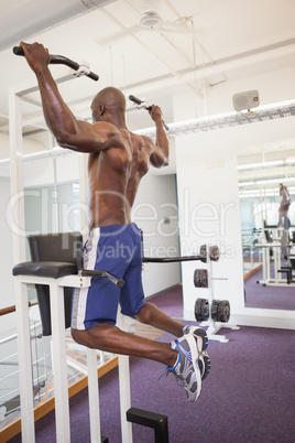 Male body builder doing pull ups at the gym