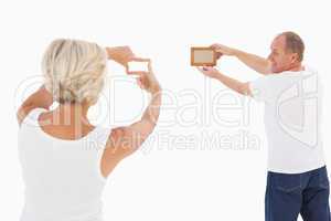 Mature couple hanging up picture frame