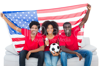 Happy football fans in red sitting on couch with usa flag