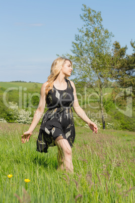 Pretty blonde in sundress walking through field