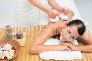 Peaceful brunette enjoying a herbal compress massage smiling at