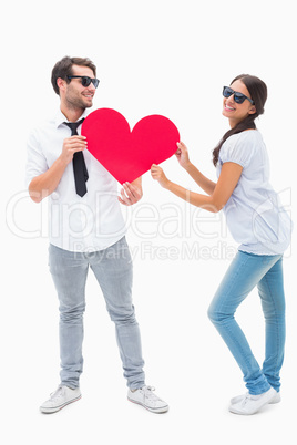 Hipster couple smiling at camera holding a heart