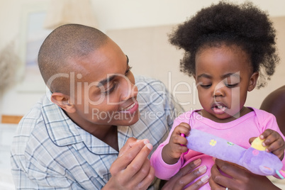 Happy parents playing with baby girl on bed together