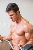 Shirtless muscular man lifting barbell in gym