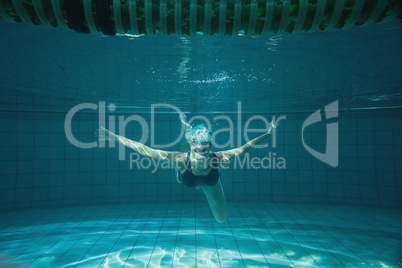 Athletic swimmer smiling at camera underwater