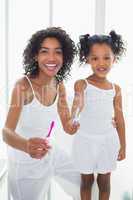 Pretty mother and daughter holding toothbrushes