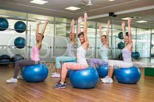 Fitness class sitting on exercise balls in studio