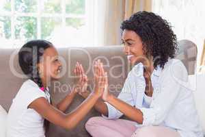 Pretty mother playing clapping game with daughter on couch