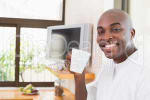 Happy man in bathrobe drinking coffee