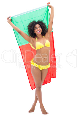 Girl in yellow bikini holding up portugal flag smiling at camera