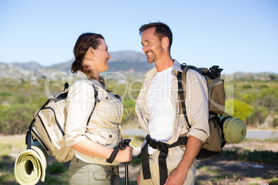 Hiking couple smiling at each other in the countryside