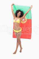 Athletic girl in yellow bikini holding portugal flag