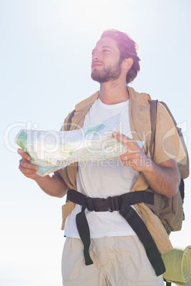 Handsome hiker holding map on mountain trail