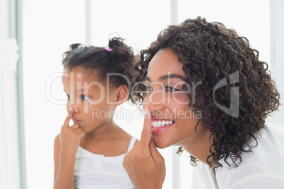 Pretty mother putting face cream on with her daughter
