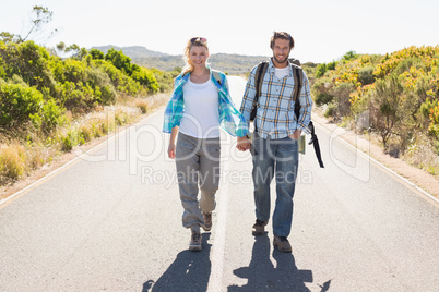 Attractive couple standing on the road holding hands smiling at