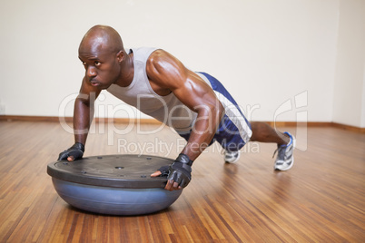 Muscular man doing push ups in gym