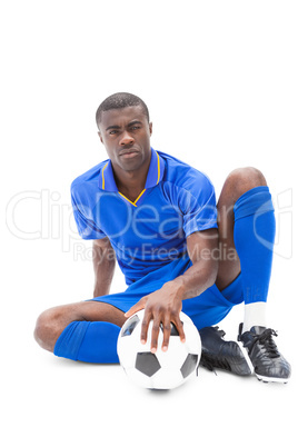 Football player sitting on the ground holding ball