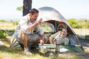 Outdoorsy couple cooking on camping stove outside tent