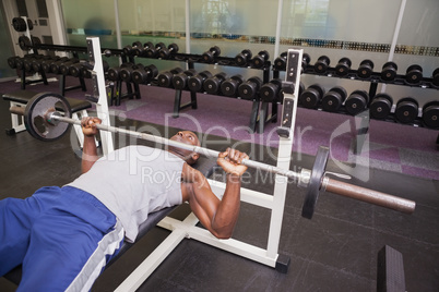 Determined muscular man lifting barbell in gym